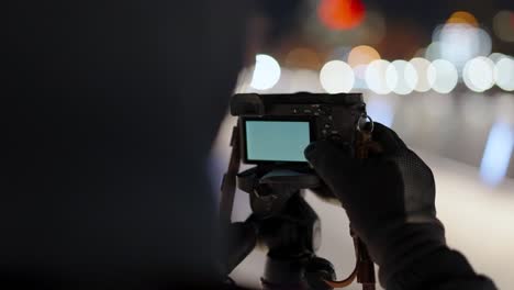 Young-photographer-takes-a-long-exposure-photo-at-night-in-the-cold-wearing-gloves-with-lots-of-bokeh