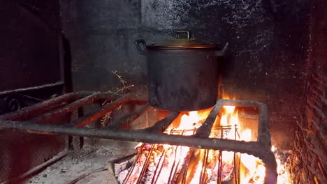 Food-cooked-in-black-pot-made-on-fire,-bonfire-and-black-walls-of-fire