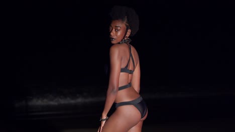 Junge-Frau-Genießt-Die-Meeresbrise-In-Einem-Schwarzen-Bikini-Nachts-Am-Strand-In-Der-Karibik