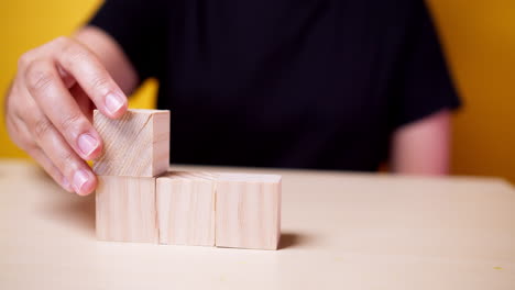 Hand-putting-wood-cube-on-top-of-wood-block-stacking-as-step-stair