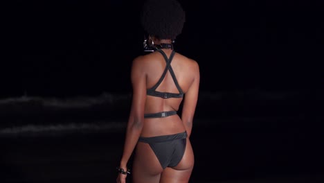 Eine-Sexy-Schwarze-Frau-Geht-Nachts-In-Einem-Schwarzen-Bikini-Zu-Den-Meereswellen-Hinaus