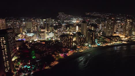 Nächtliche-Luftaufnahme-Von-Waikiki-Mit-Weihnachtslichtern-Und-Hotels-Auf-Oahu-Hawaii-Nächtliche-Skyline-Und-Ozean-Mit-Nachbarschaften-Im-Rücken