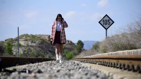 Stylish-woman-walking-along-a-train-track
