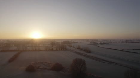 Drone-flying-low-over-frozen-farmlands-in-the-winter-at-sunrise-in-the-netherlands-in-4k
