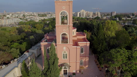 rising-up-reveal-beautiful-pink-church-surrounded-by-trees---drone-shot