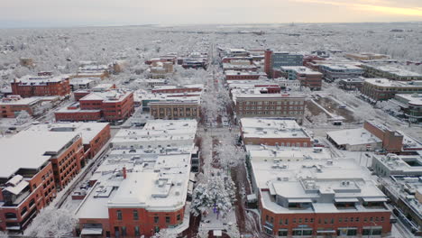 Low-drone-shot-moving-forward-of-Boulder-Colorado-and-downtown-Pearl-Street-after-large-winter-snow-storm-covers-trees,-homes,-streets,-and-neighborhood-in-fresh-white-snow