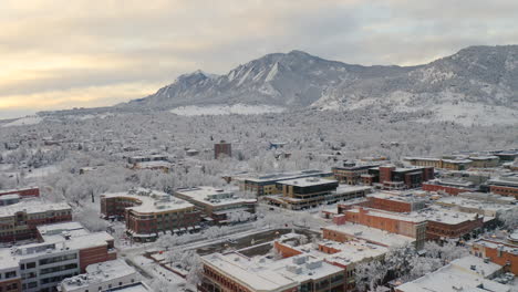 Low-drone-shot-moving-forward-of-Boulder-Colorado,-rocky-Flatiron-mountains,-and-Pearl-Street-after-large-winter-snow-storm-covers-trees,-homes,-streets,-and-neighborhood-in-fresh-white-snow