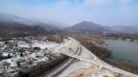 Highway-exist-near-a-small-town-in-winter-snow,-60fps-US-to-Canada,-Ohio,-arial-drone-shot,-with-mountains-in-the-background