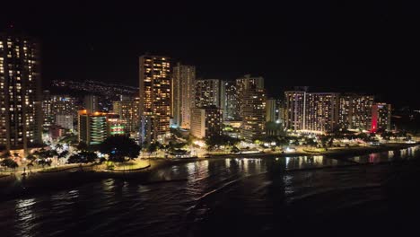 Waikiki-drohnenluftaufnahmen-Bei-Nacht-Mit-Hellen-Gebäuden-Und-Viel-Licht-Mit-Verkehr-Und-Palmen-Oahu-Hawaii