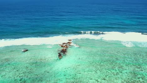 Mahe-Seychelles-Anse-Forbans-Beach,-Tiro-De-Drone-Moviéndose-Hacia-Aguas-Turquesas-De-Rocas-Medias
