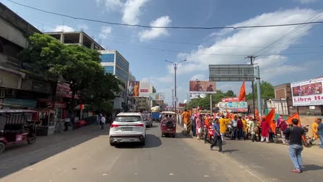 POV-shot-of-two-way-road-beside-an-auto-stand-and-a-procession-passing-by-in-Dhanbad,-India-on-a-bright-sunny-day