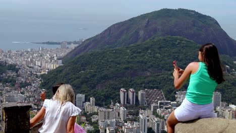 Tourists-at-Sugarloaf-Mountain-overlook-taking-pictures-of-Rio-de-Janeiro-city,-beaches-and-mountains