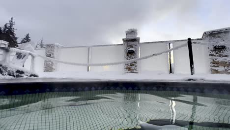 Heißer-Dampf,-Der-Aus-Einem-Heißen-Pool-In-Den-Heißen-Quellen-Von-Halcyon-Britisch-Columbia-Aufsteigt,-Mit-Einem-Hellgelben-Sonnenuntergang,-Der-Durch-Das-Mit-Frost-Bedeckte-Glas-Kommt
