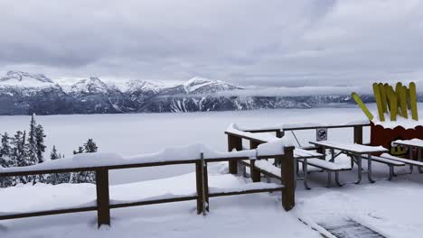 Vista-Panorámica-Sobre-La-Cordillera-Al-Sur-De-La-Cima-Del-Monte-Mackenzie-Revelstoke-Columbia-Británica-Canadá-Con-Una-Capa-De-Nubes-Bajas-Y-Barandillas-Cubiertas-De-Nieve-Con-Esquís-Amarillos-En-El-Fondo