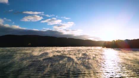 Fog-on-lake,-golden-sunlight-rising,-Steam-fog-rising-from-a-lake,-early-morning-arial-drone-shot-60fps,-with-blue-sky
