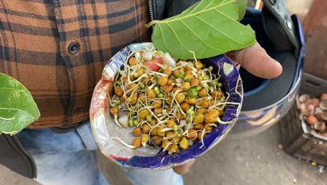 Close-up-shot-of-fresh-made-sprout-salad-in-hands-of-a-local-from-a-roadside-stall-at-daytime