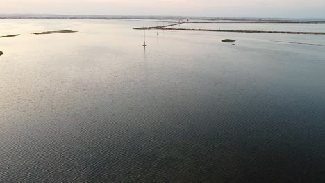 Drone-shot-of-power-lines-passing-through-a-shallow-bay-of-water