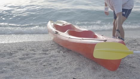 A-man-prepares-a-kayak-for-a-ride-near-a-beautiful-beach