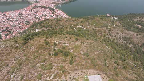 Clip-Aéreo-Sobre-Una-Montaña-Que-Revela-La-Ciudad-Y-El-Lago-De-Kastoria,-En-El-Norte-De-Grecia