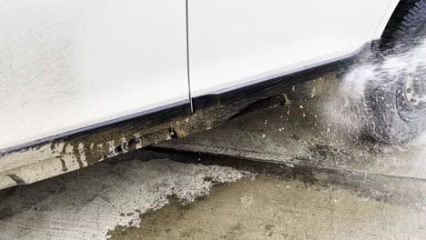 Hosing-down-and-spraying-off-tons-of-dry-dirt-and-mud-grime-on-a-white-overlanding-SUV-with-sprays-of-water