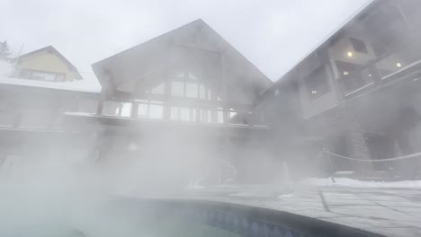 Hot-steam-blowing-in-the-wind-off-of-the-hot-pools-at-Halcyon-Hot-Springs-Resort-British-Columbia-with-the-lodge