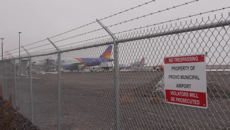 Airplane-at-the-gate-behind-the-fence-at-Provo-Municipal-Airport---snow,-sleet-and-rain