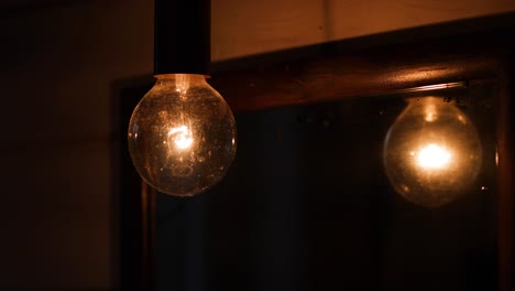 Old-dusty-incandescent-light-bulb-reflecting-in-the-mirror-in-a-dim-lit-room