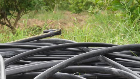 Close-Up-View-Of-Coiled-Up-Black-Hosepipes-Laying-On-Ground
