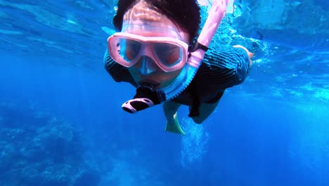 Close-up-of-young-adventurous-woman-snorkelling-over-tropical-coral-reef
