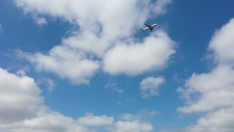 Plane-approaching-airport-landing-against-blue-sky-clouds,-panning