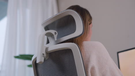 Rear-Side-View-Of-A-Woman-Seated-In-An-Office-Chair-Working-From-Home