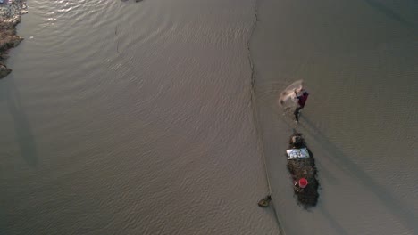 Fisherman-cast-net-fishing-in-Tonle-Sap-waterway-in-Asia,-Aerial-birds-eye-view-during-late-afternoon-setting-sun,-slow-mo-copy-space