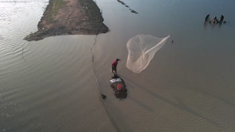 Fisherman-cast-net-fishing-in-Tonle-Sap-waterway-in-Asia,-Aerial-birds-eye-view-during-late-afternoon-setting-sun,-slow-mo-static