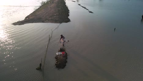Fisherman-cast-net-fishing-in-Tonle-Sap-waterway-in-Asia,-Aerial-birds-eye-view-during-late-afternoon-setting-sun,-slow-mo