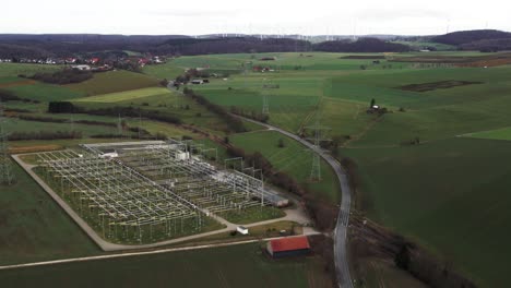 Kritische-Infrastruktur:-Luftaufnahme-Von-Stromleitungen,-Die-Windmühlen-Mit-Einem-Umspannwerk-Im-Deutschen-Stromnetz-Im-Sauerland-Verbinden