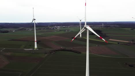 Critical-Energy-Production:-Rotating-Windmills-on-a-Field-in-Sauerland,-Germany,-Aerial-Panning-Sho