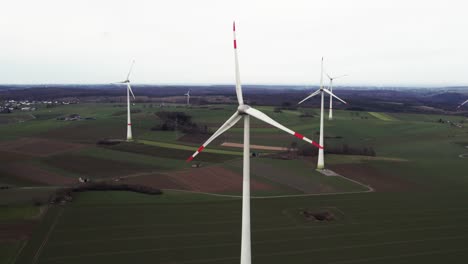 Critical-Energy-Production:-Rotating-Windmills-on-a-Field-in-Sauerland,-Germany,-Aerial-backwards