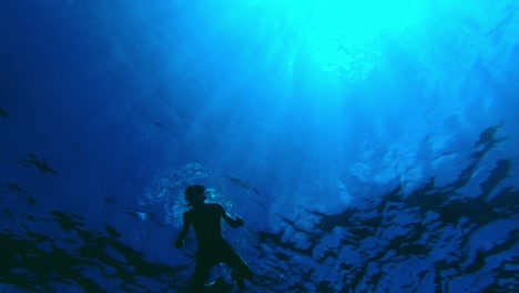 Perspectiva-Submarina-única-De-Un-Tipo-En-Forma-Nadando-En-Los-Tonos-Oceánicos-De-Azul-Con-Rayos-De-Sol-Atravesando-El-Agua
