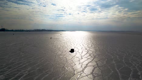Winterfischerzelt-Auf-Zugefrorenem-See,-Mit-Sonne-Im-Hintergrund-Und-Textur-Eisiger-See,-See-St-Clair,-60fps-Luftdrohnenaufnahme