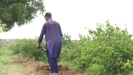 Agricultor-Paquistaní-Visto-Empujando-Un-Cultivador-De-Gasolina-Sobre-Suelo-En-Sindh,-Pakistán