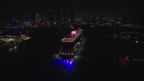 Aerial-back-view-of-huge-ship-arriving-to-cruise-terminal-in-Miami-port-at-night