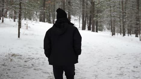 Hombre-Vestido-De-Negro-Caminando-Por-Un-Bosque-Blanco-De-Invierno-Cubierto-De-Nieve