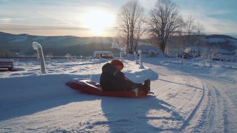 A-boy-is-sledding-in-the-snow-during-Christmas-and-a-beautiful-sunset-in-Norway