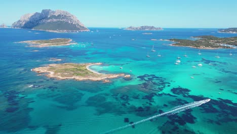 Tavolara-and-Cavalli-Island-surrounded-by-boats-and-turquoise-blue-sea-in-Sardinia,-Italy---Aerial-4k