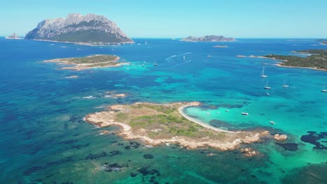 Tavolara-Island-surrounded-by-boats-and-turquoise-blue-sea-in-Sardinia,-Italy---Aerial-4k-Circling