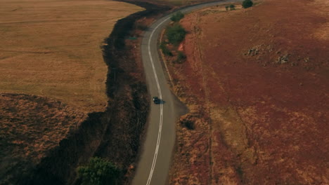 High-wide-Drone-shot-following-a-black-Austin-Westminster-vintage-car-driving-through-the-hills-of-south-africa-during-dry-winter-4K