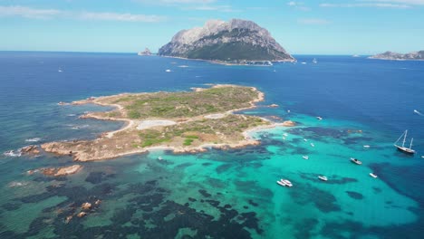 Tavolara-Island-and-Isola-Piana-surrounded-by-boats-and-turquoise-blue-sea-in-Sardinia,-Italy---Aerial-4k