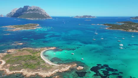 Tavolara-Island-surrounded-by-boats-and-turquoise-blue-sea-in-Sardinia,-Italy---Aerial-4k
