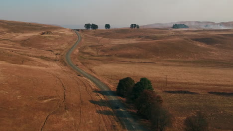 Drone-shot-of-a-vintage-black-Austin-Westminster-car-driving-through-the-hills-of-south-africa-during-dry-winter-conditions
