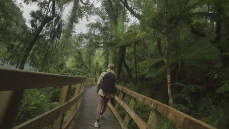 Blond-woman-traveler-exploring-wooden-boardwalk-trail-at-Hokitika-Gorge